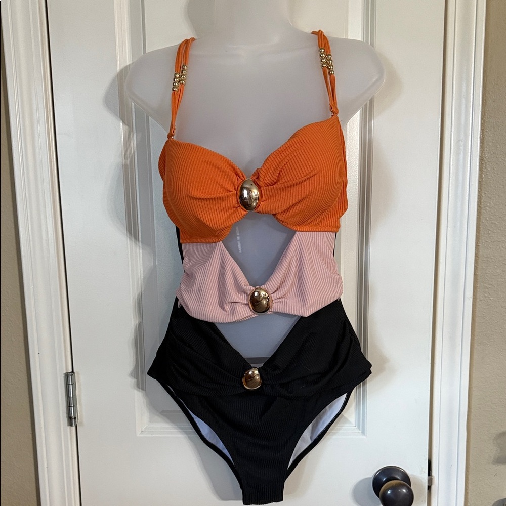 One piece with cut outs and gold accent pieces size L. NWT